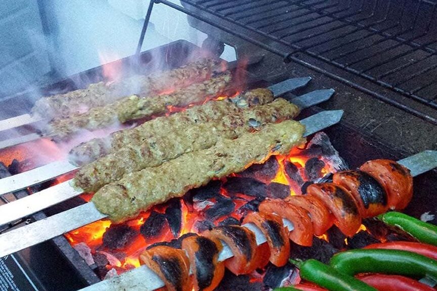 کباب کوبیده سیخی با سبزیجات رنگارنگ روی زغال گداخته